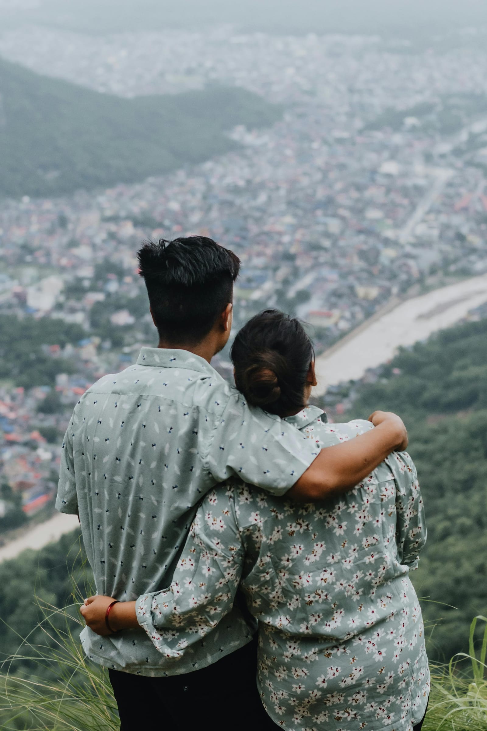Two people overlooking a city from a hillside