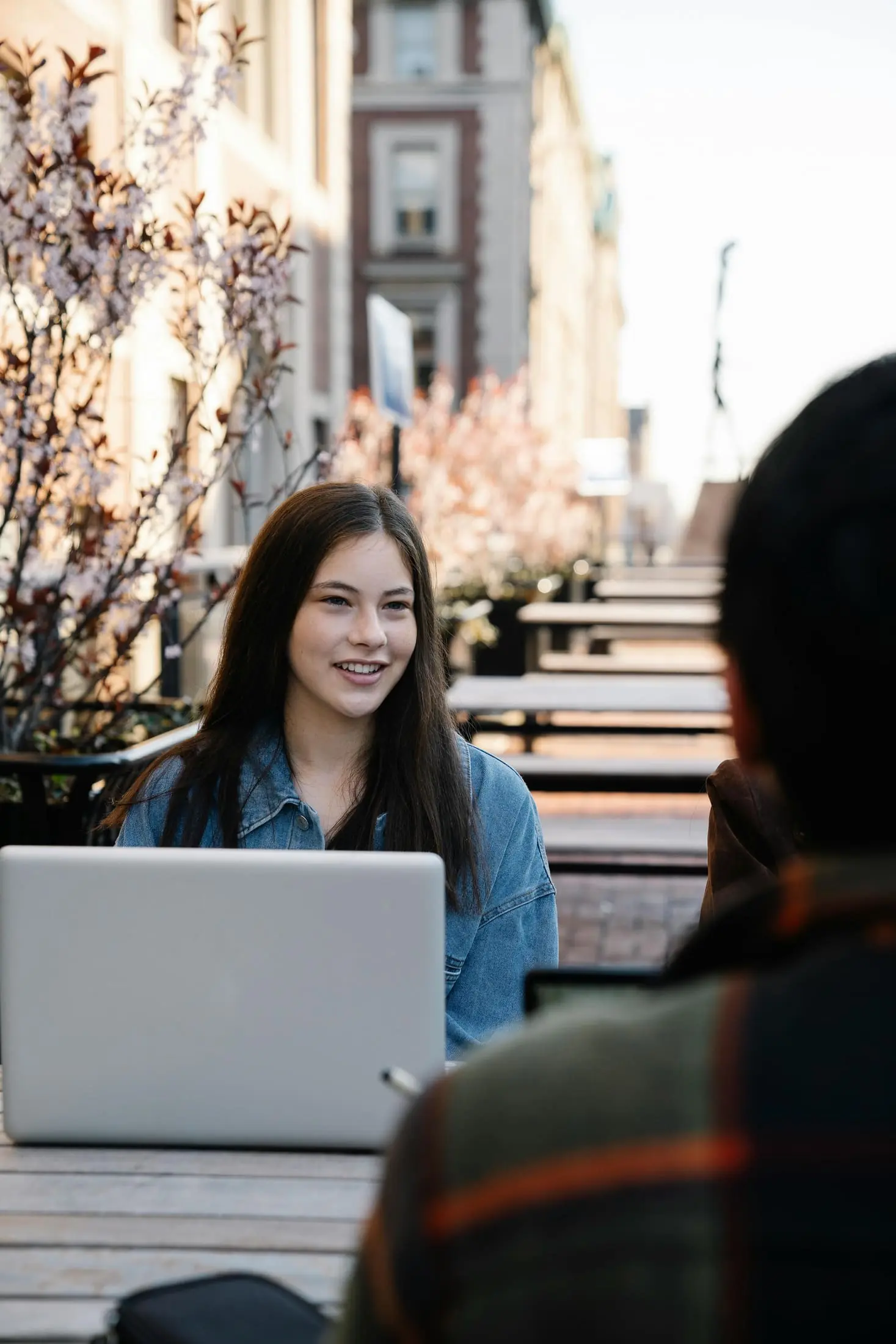 People talking at an outdoor table with a laptop
