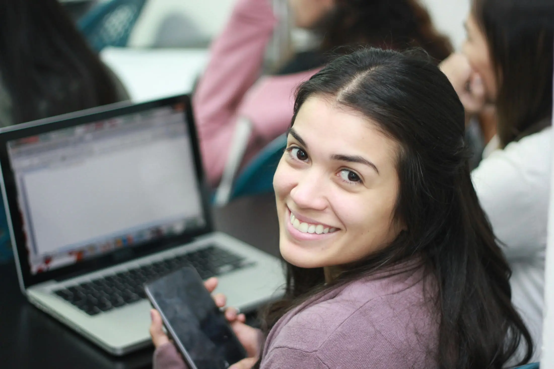 Student holding a phone next to a laptop